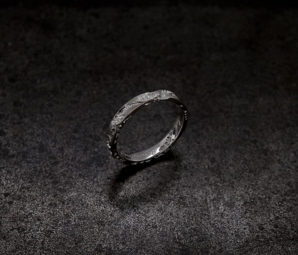 Wave Band (4mm) ring displayed on a textured dark surface, showcasing its intricate design.