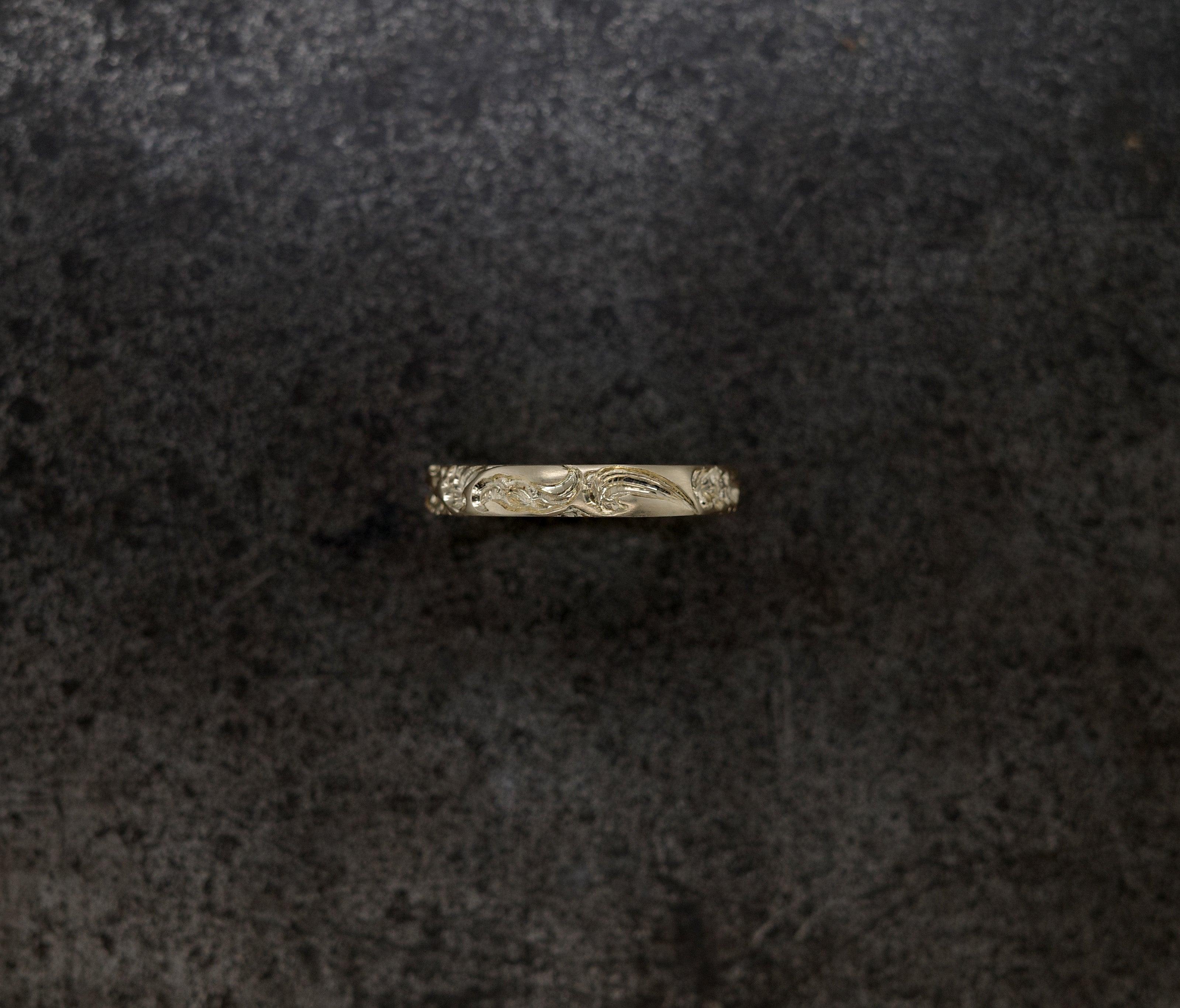 Wave Band (4mm) ring featuring intricate floral engraving on a dark textured background.