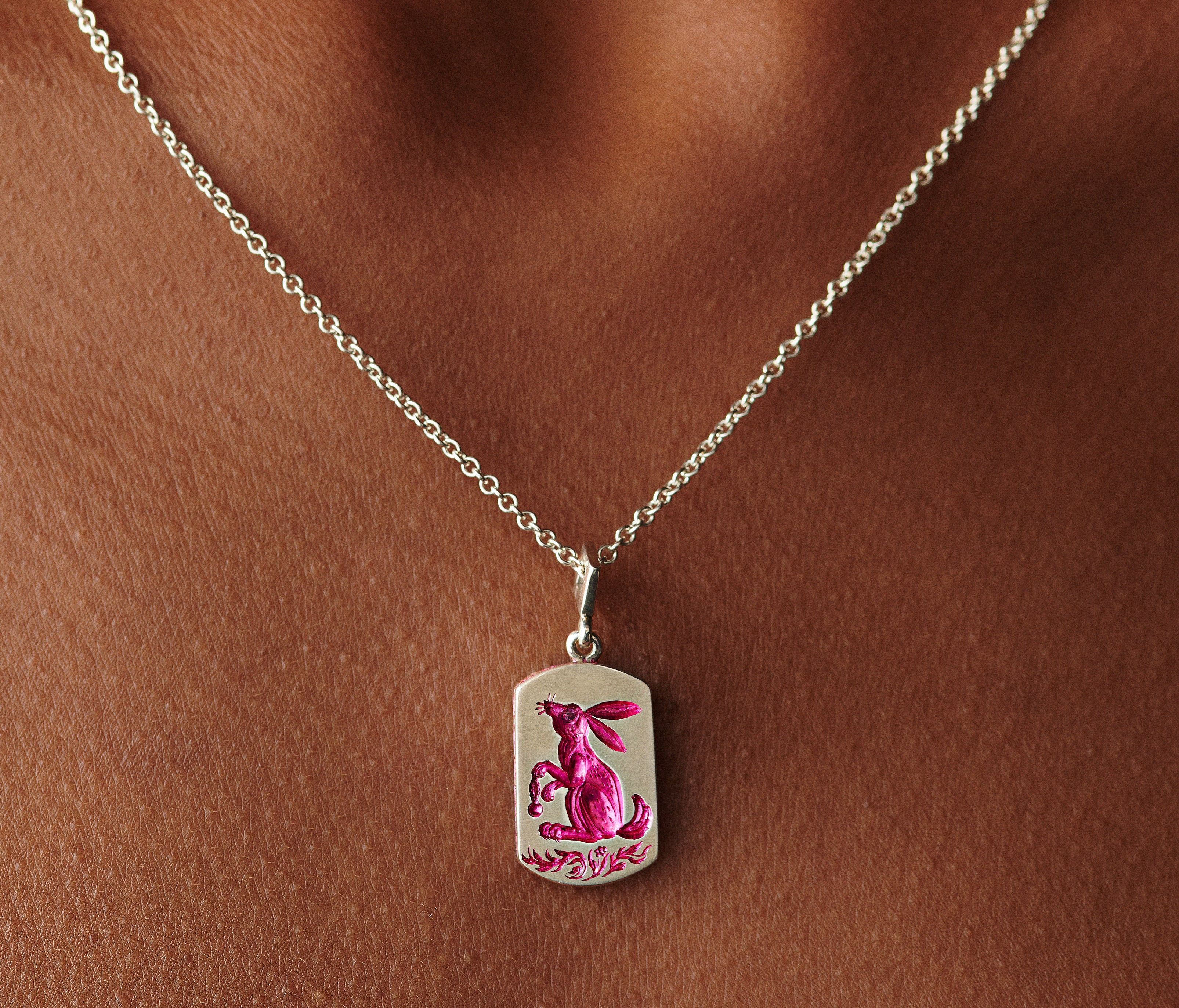 Silver pendant necklace featuring a hand-engraved rabbit with pink ceramic plating and a delicate chain pattern edge