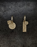 Pair of gold tiny hoop earrings with engraved botanical and centipede designs on dark textured background