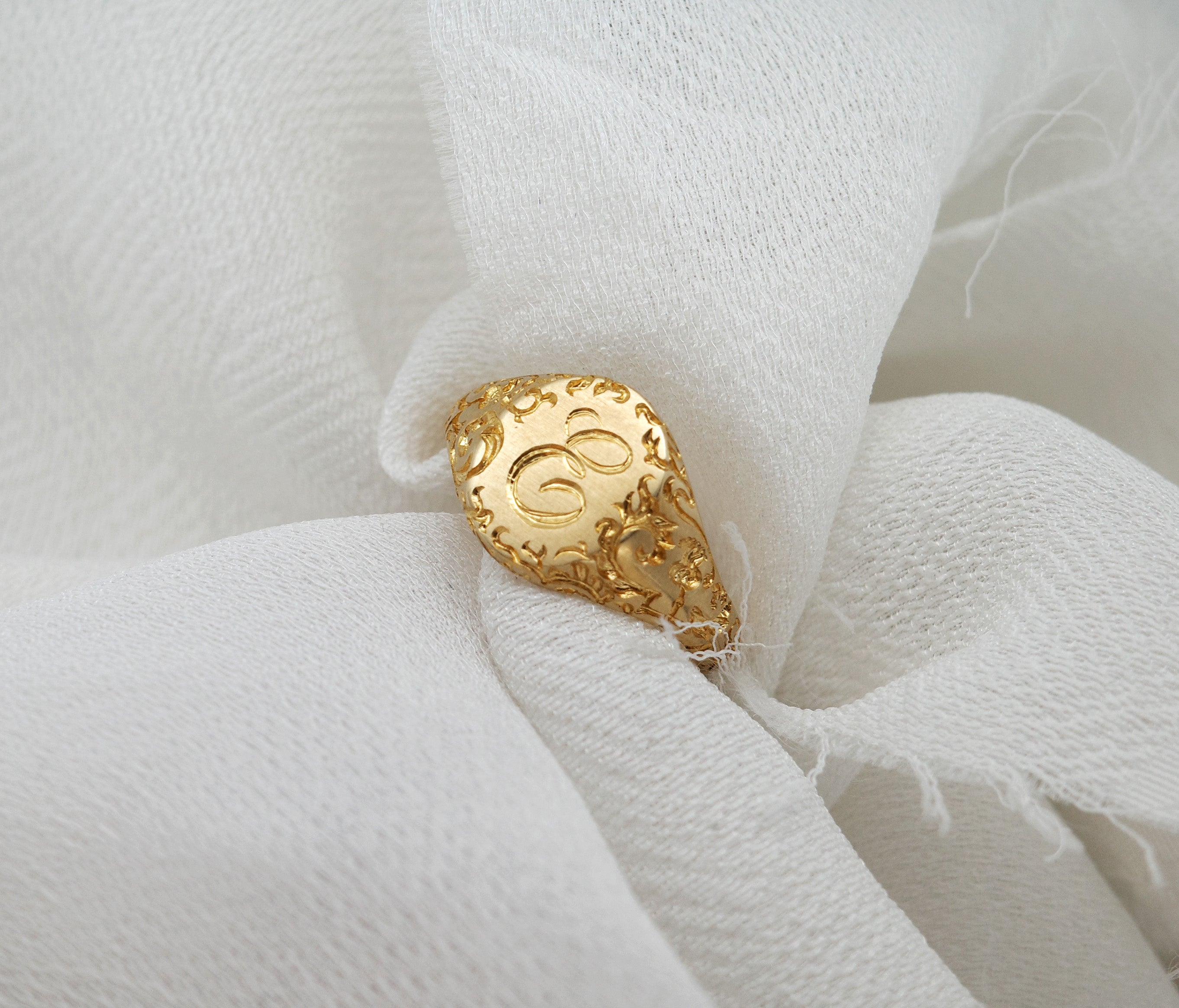 E Minor Signet Ring resting on a soft white fabric, featuring custom initials beautifully engraved.