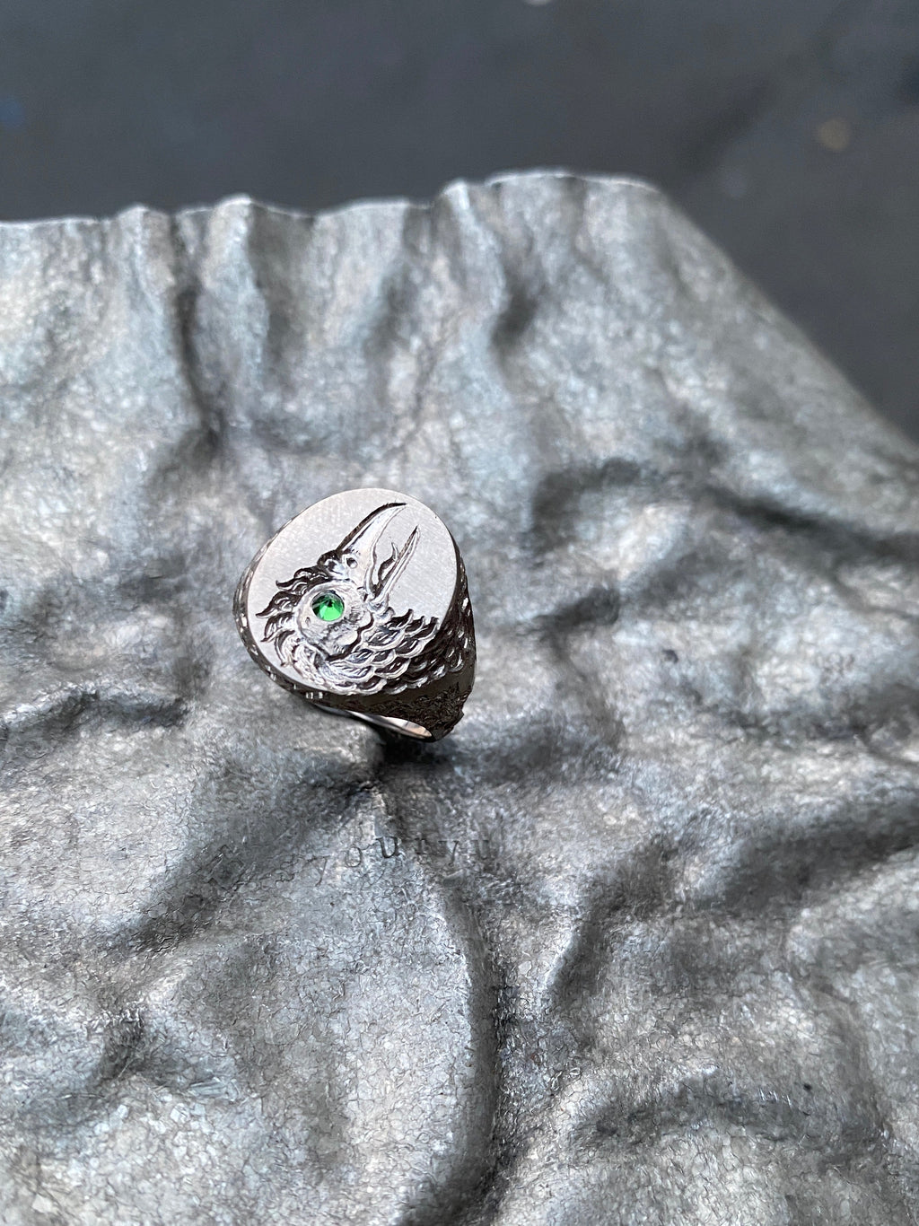 Silver ring with a green gemstone on a textured gray surface
