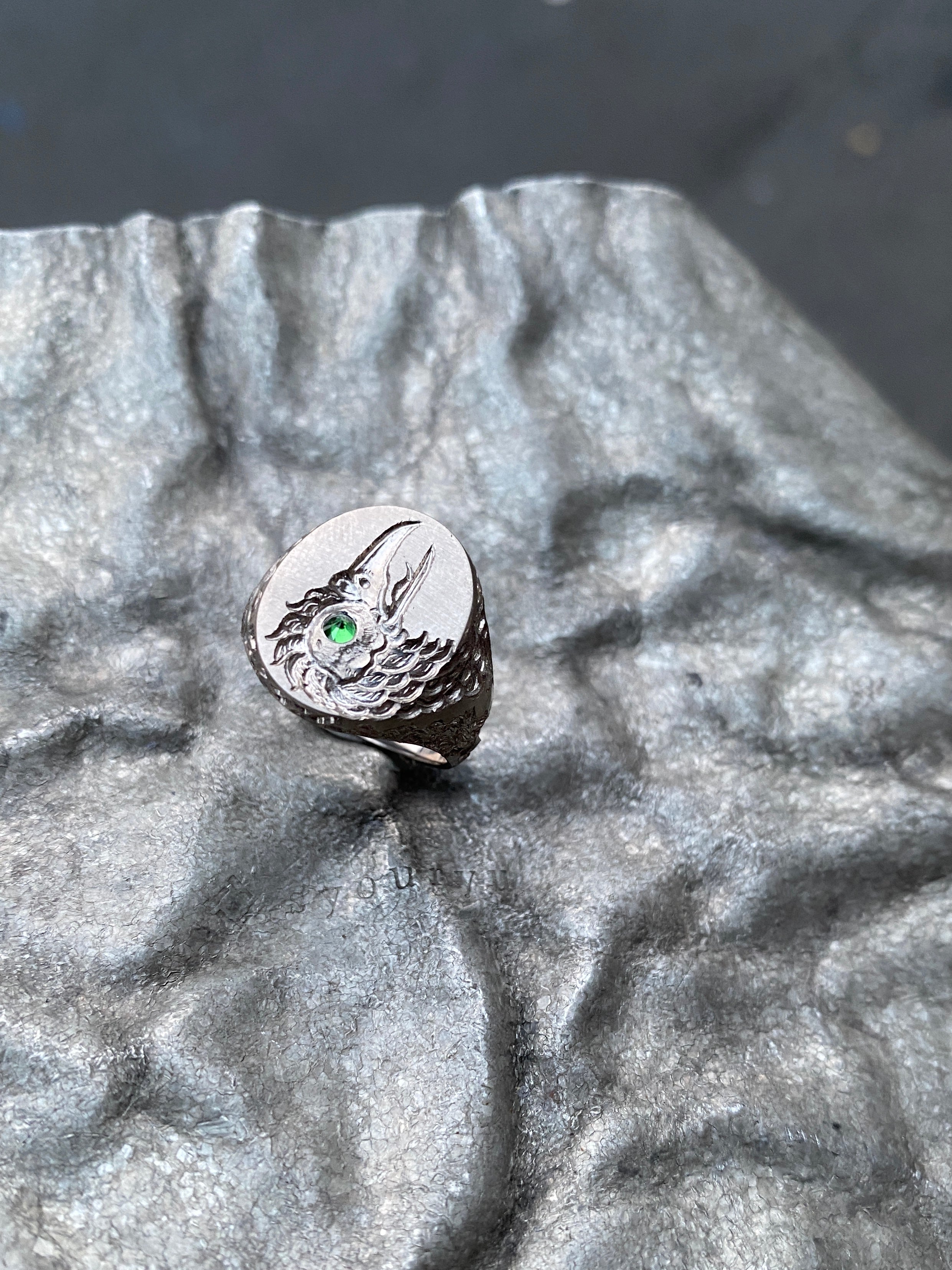 Silver ring with a green gemstone on a textured gray surface