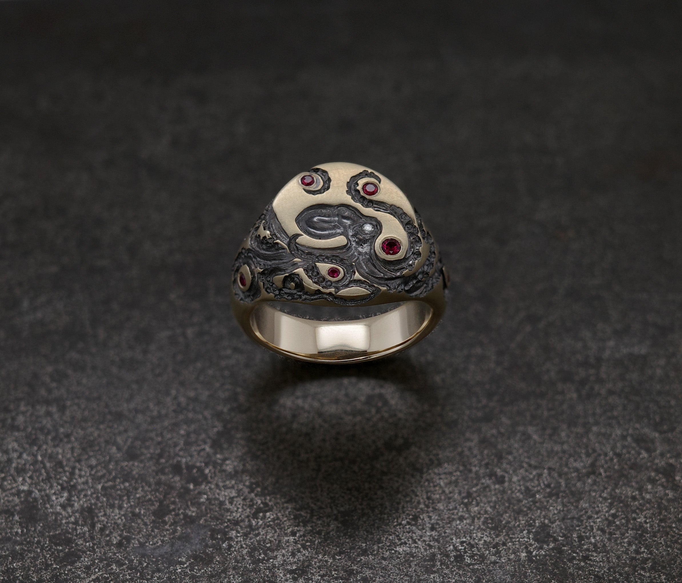 Mini Octopus Signet Ring featuring hand-engraved octopus and rubies on an artistic design.