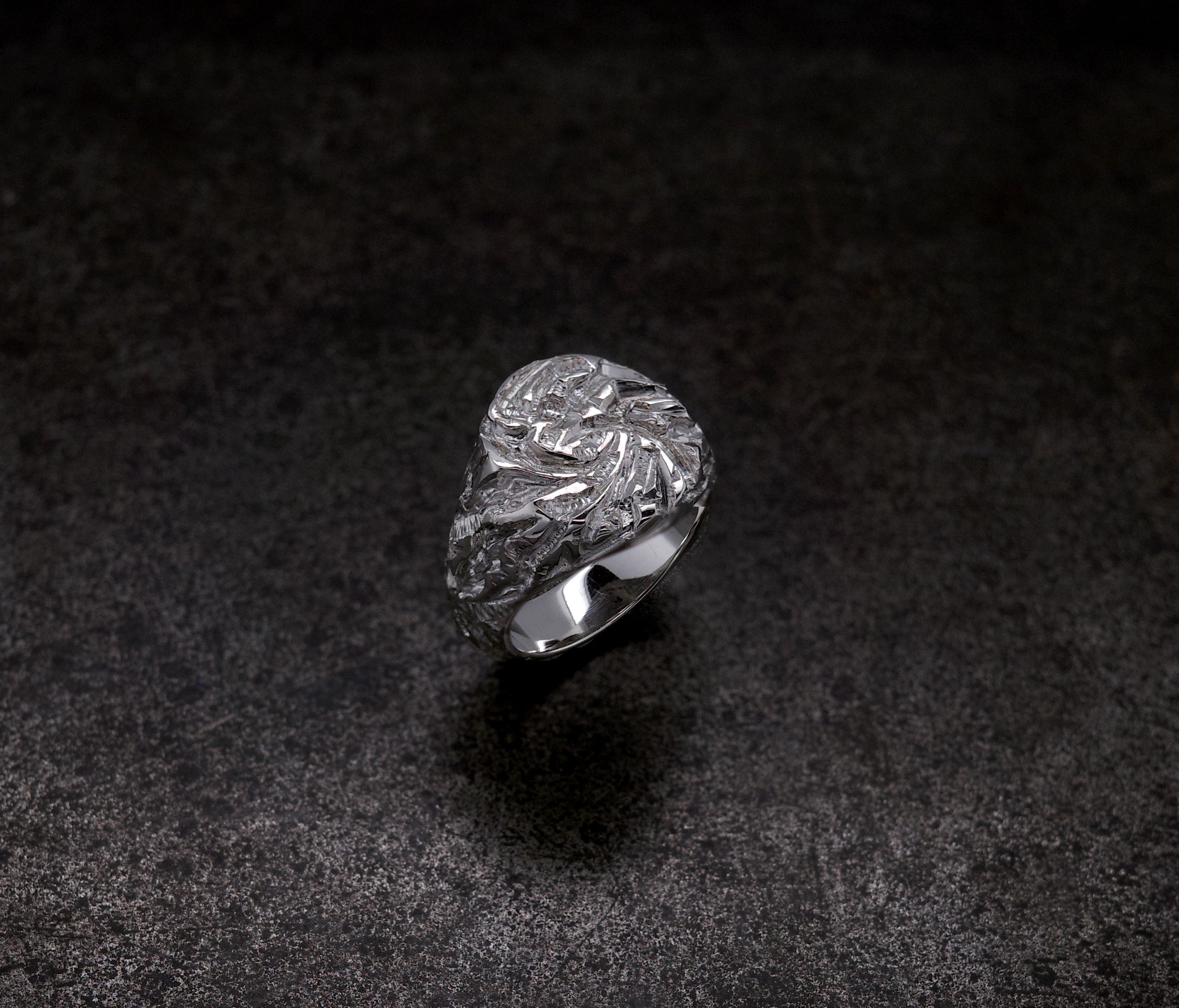 Mini Chisel Signet ring with intricate crystalline chiseled design on a dark background.