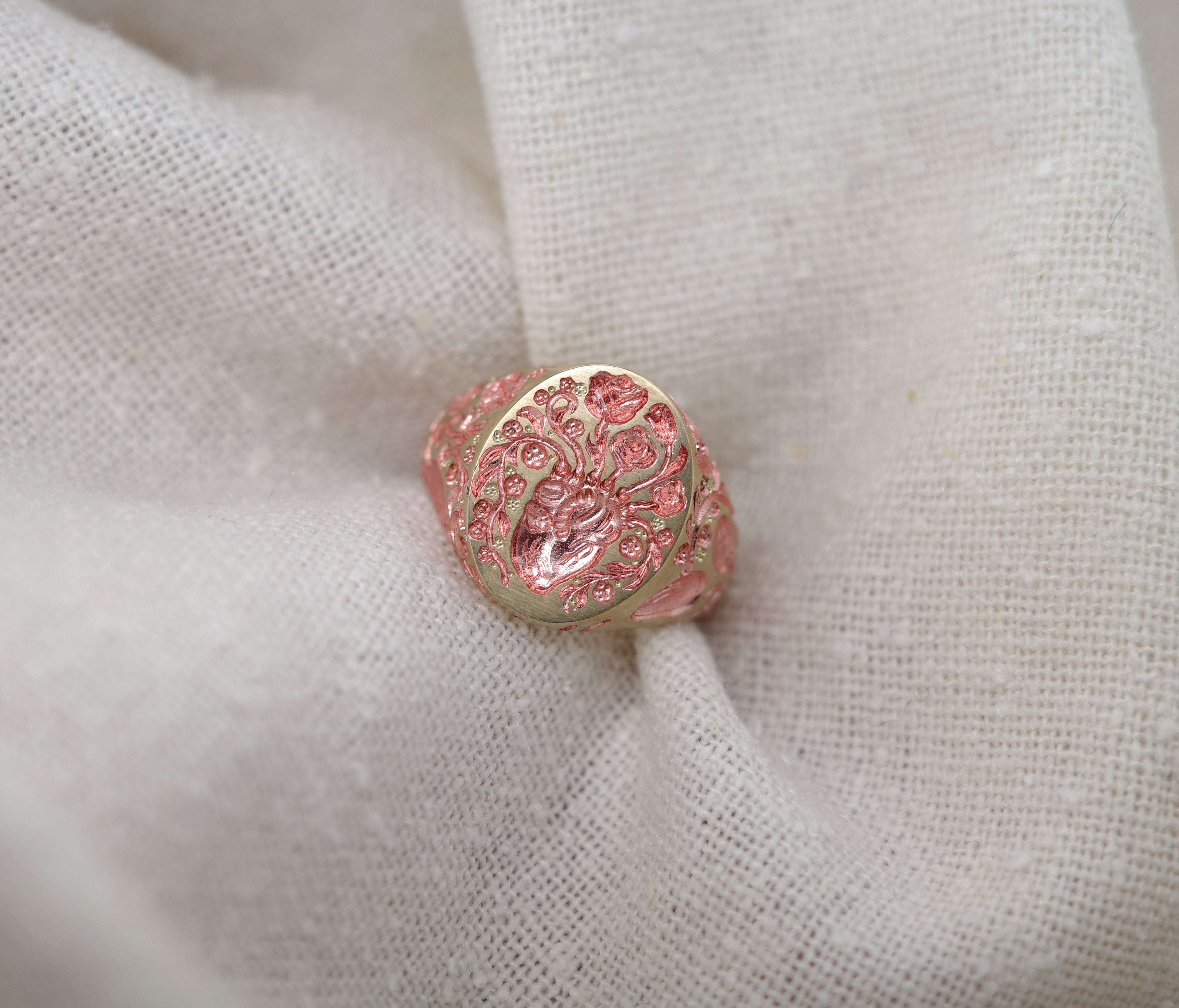 Heart Signet Mini ring with a detailed tree and heart design in rose gold on a beige fabric background.