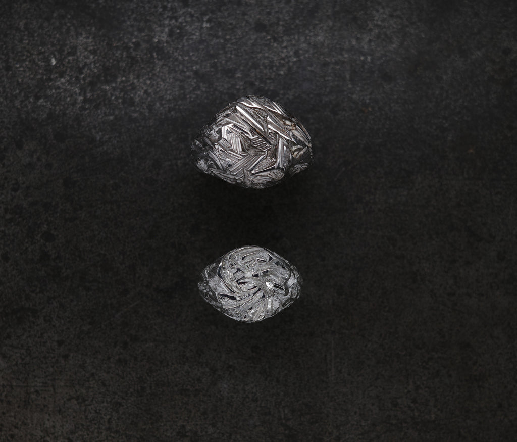 Two intricately chiseled Mini Chisel Signet rings showcasing crystalline structure on a dark background.