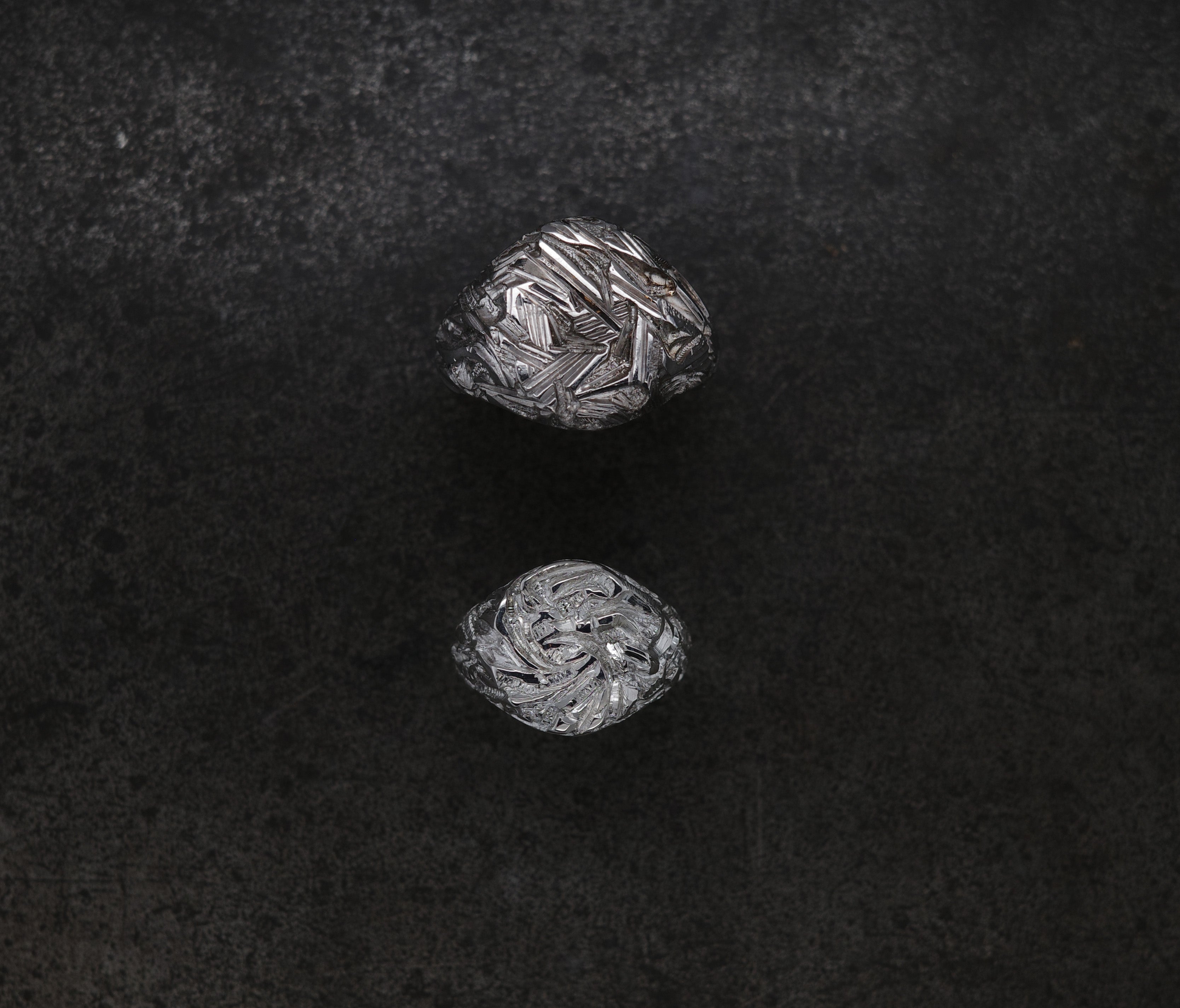 Two intricately chiseled Mini Chisel Signet rings showcasing crystalline structure on a dark background.