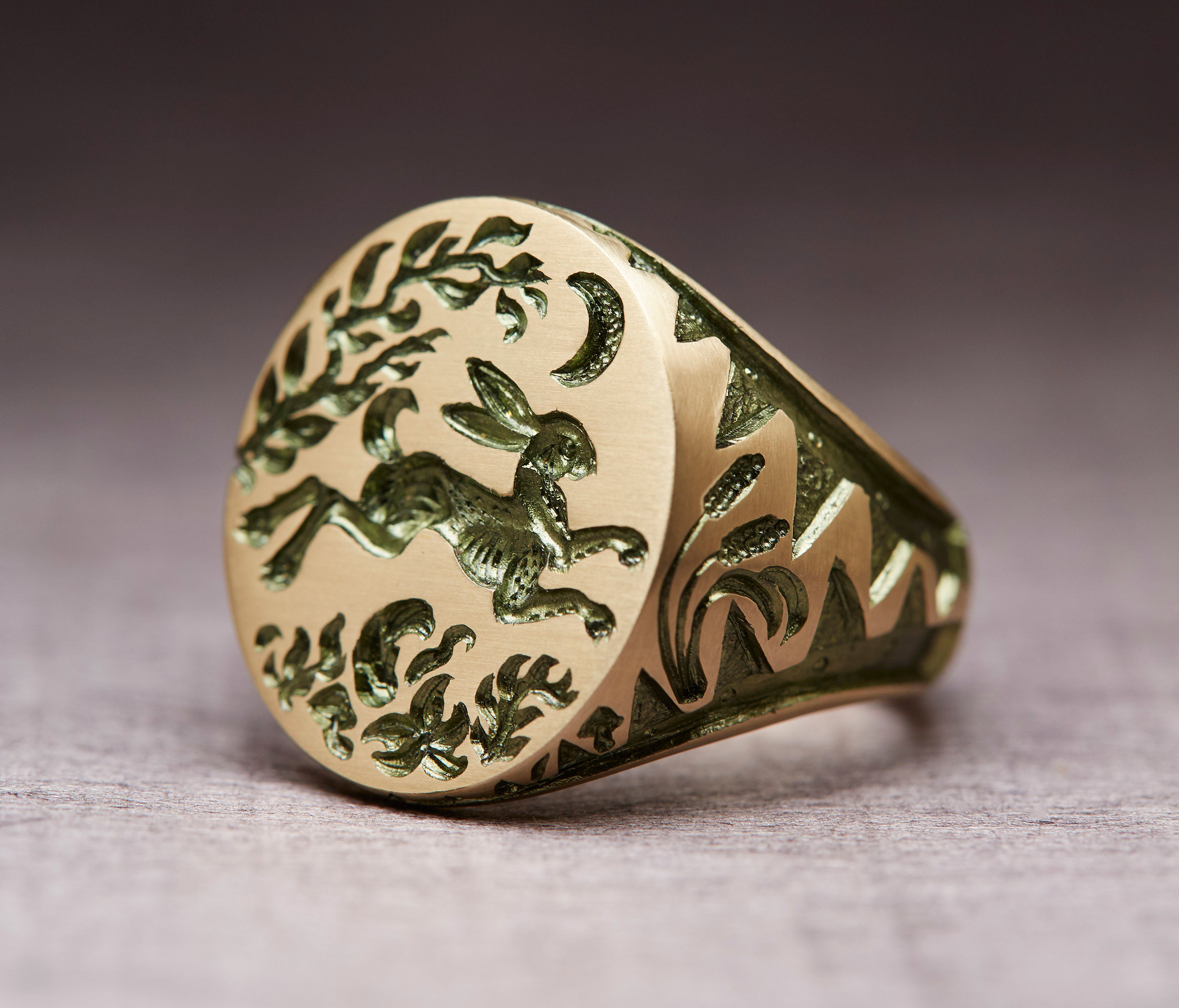Gold Hare & Trap signet ring featuring a hand engraved design of a hare escaping under the moon with foliage details.