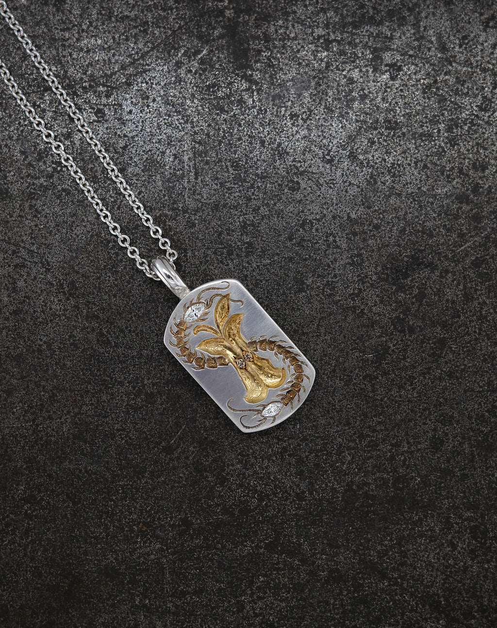 Silver necklace with a detailed Apple Core pendant featuring cognac diamond accents on a dark textured background