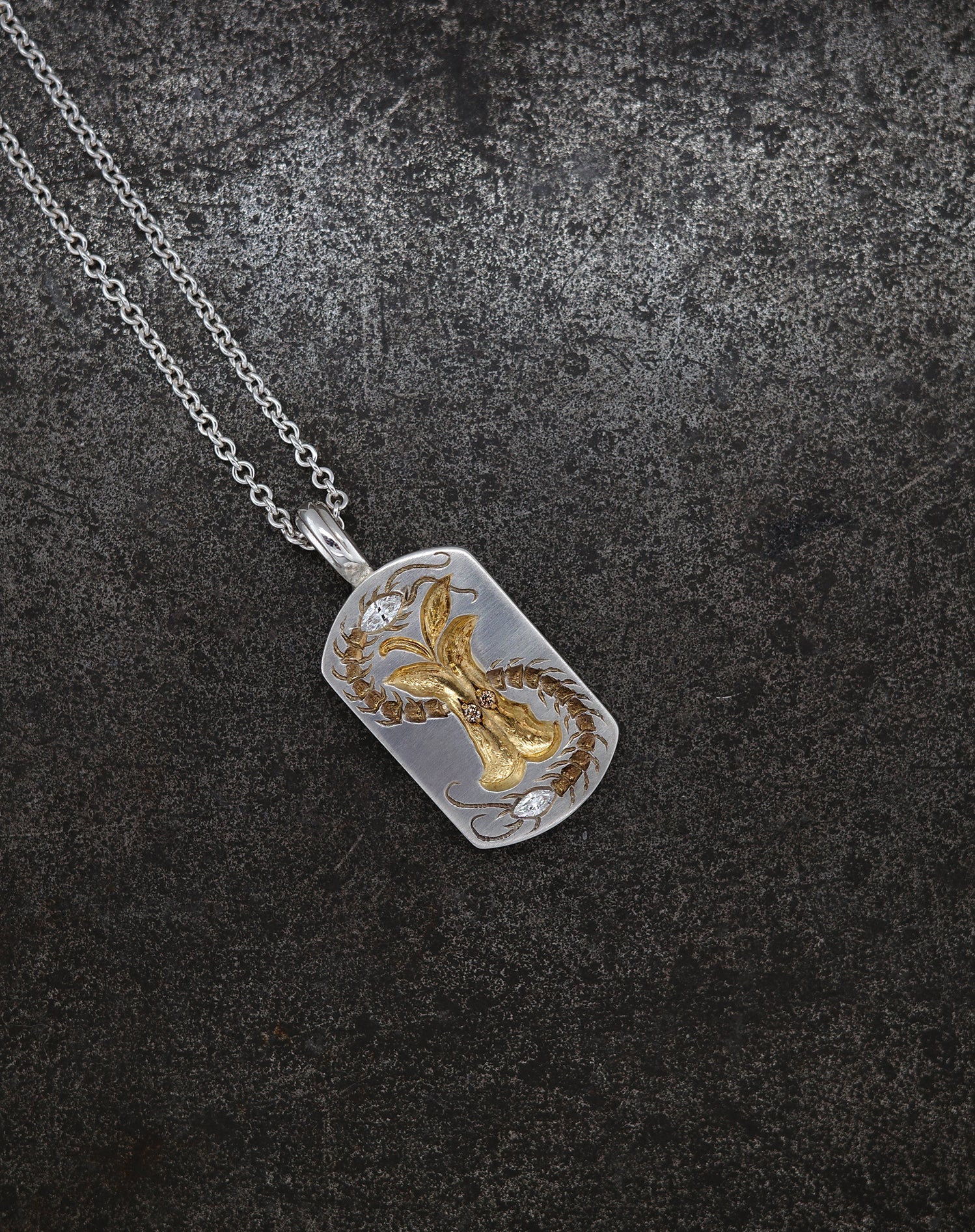Silver necklace with a detailed Apple Core pendant featuring cognac diamond accents on a dark textured background