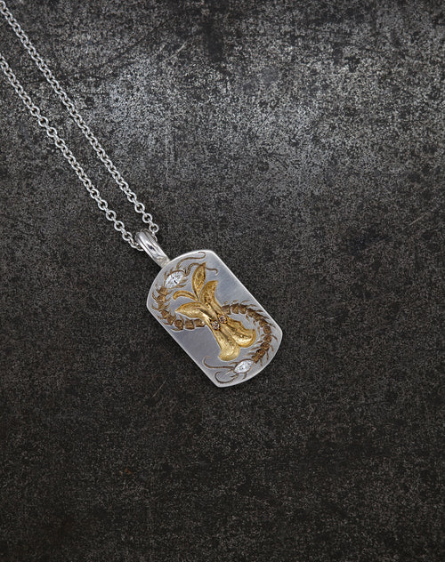 Silver necklace with a detailed Apple Core pendant featuring cognac diamond accents on a dark textured background