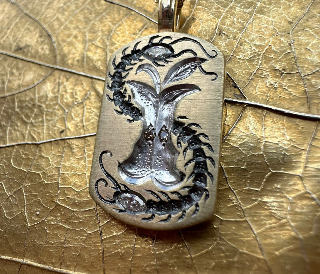 Apple Core pendant with intricate centipede design surrounding a detailed apple core engraving on a gold-toned metal background.