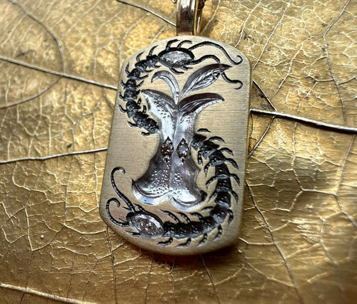 Apple Core pendant with intricate centipede design surrounding a detailed apple core engraving on a gold-toned metal background.