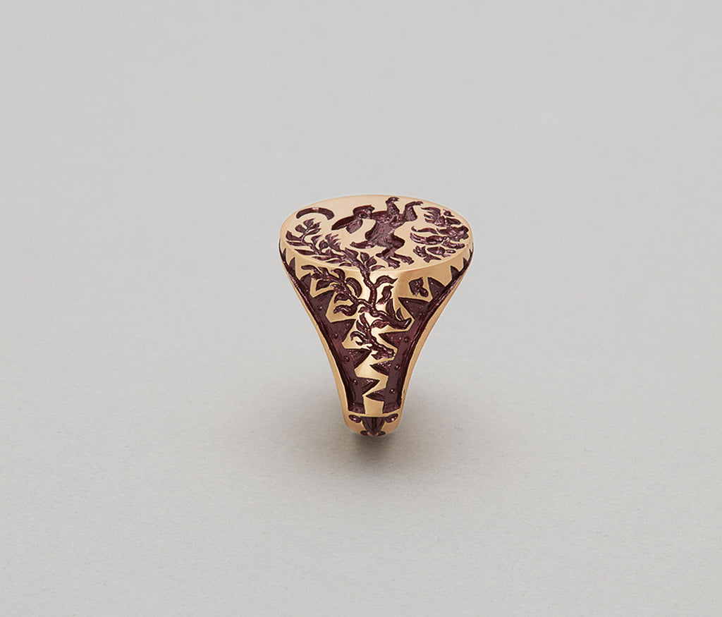 Close-up of a gold Hare & Trap signet ring with detailed engraving of a hare escaping a trap under the moon.