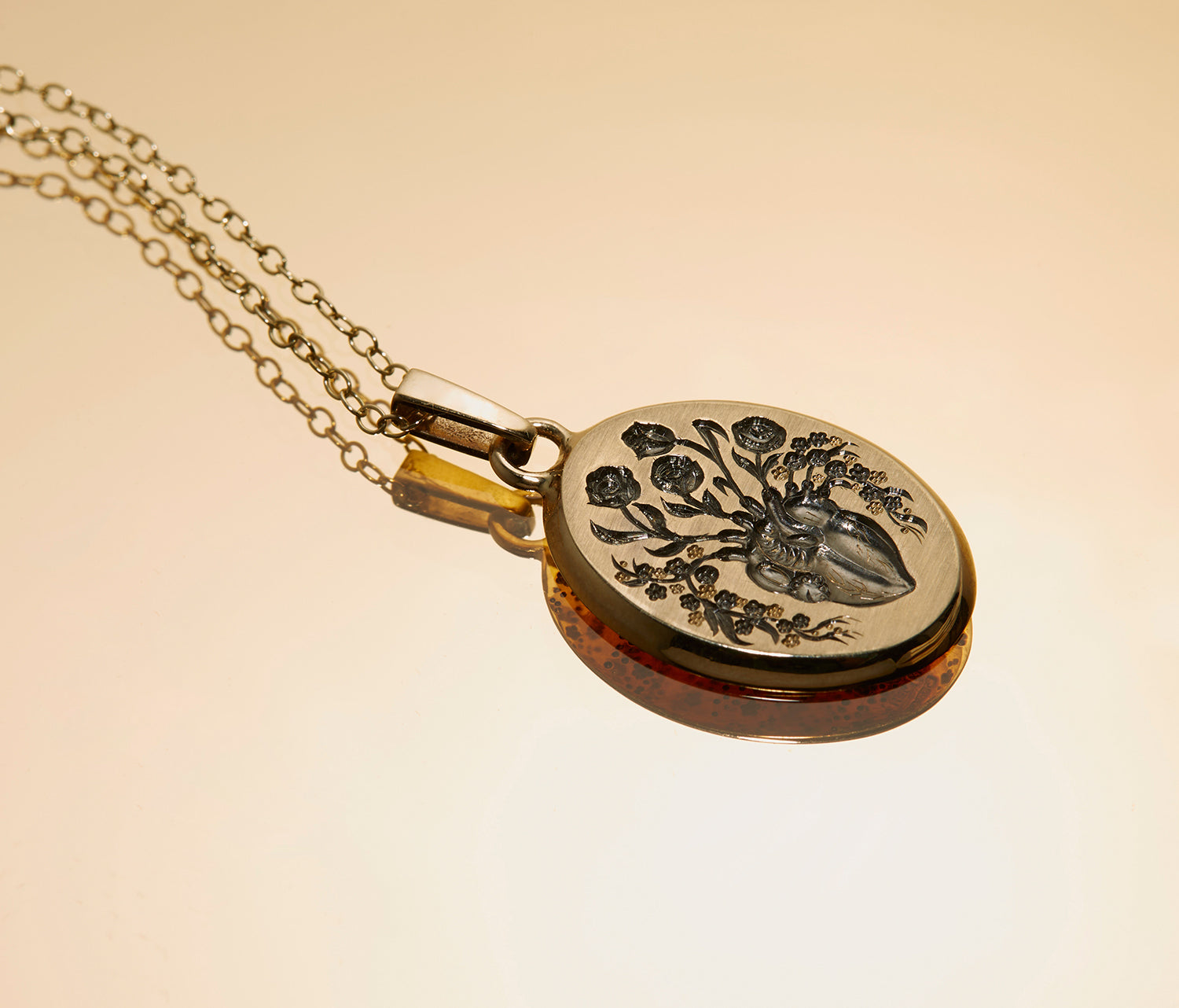 Small heart pendant necklace with engraved anatomical heart and floral design on gold chain